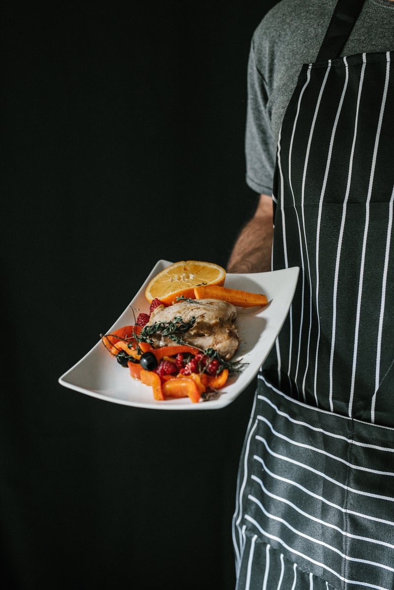 Moody Restaurant Dining and Chef Holding Chicken Dish