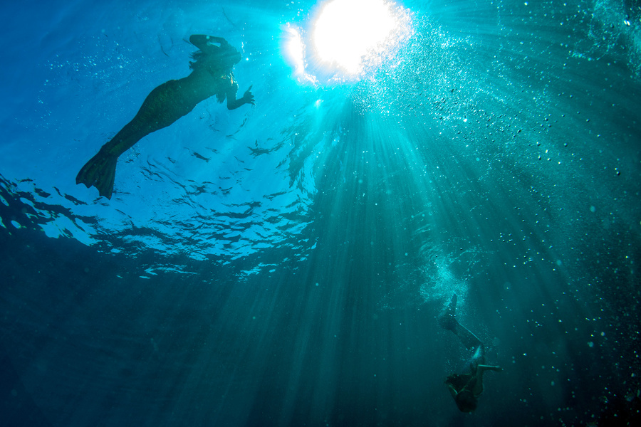 two Mermaid swimming underwater in the deep blue sea